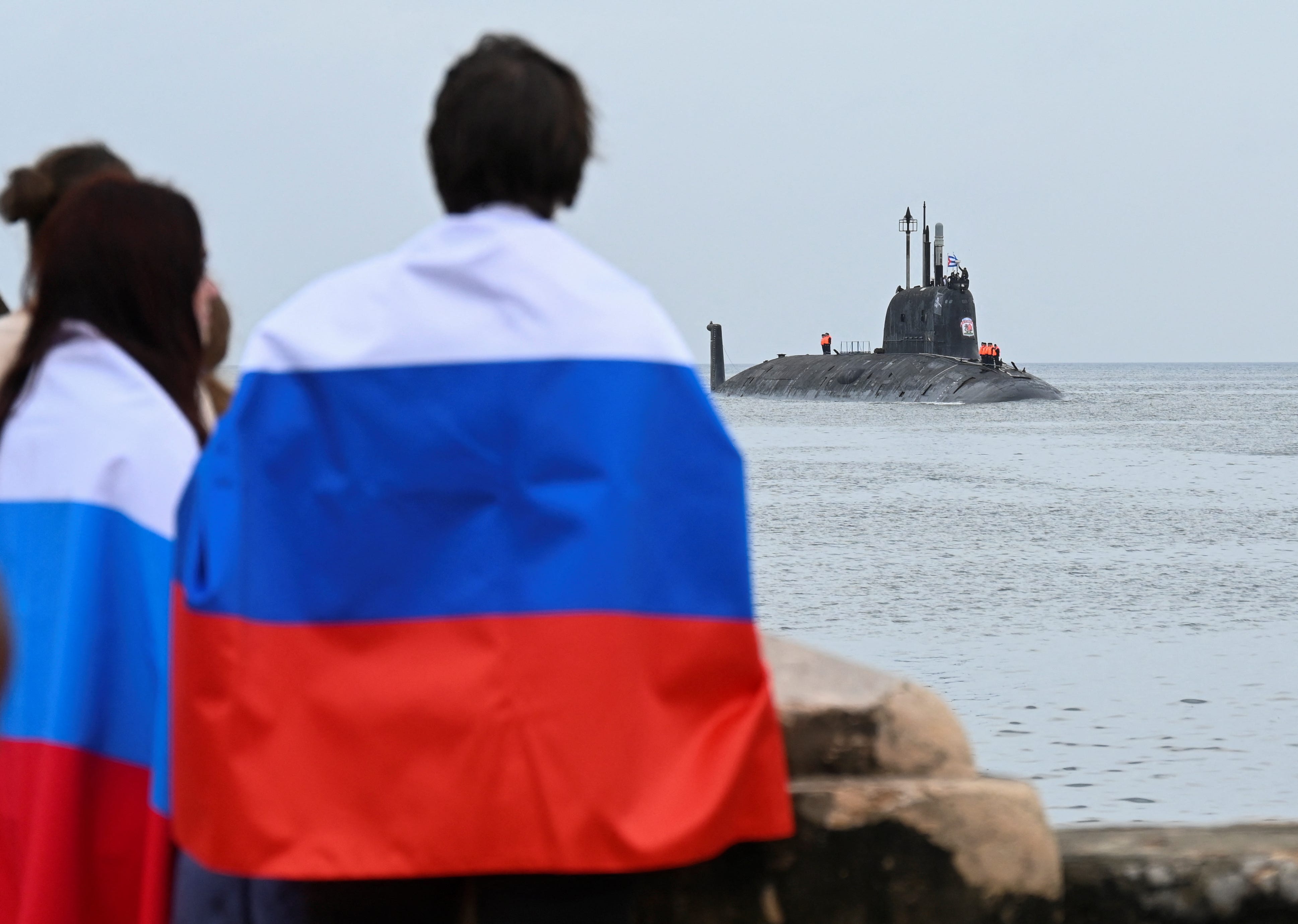 People with Russian flags look at the Russian nuclear-powered submarine Kazan arriving in Havana in 2024.