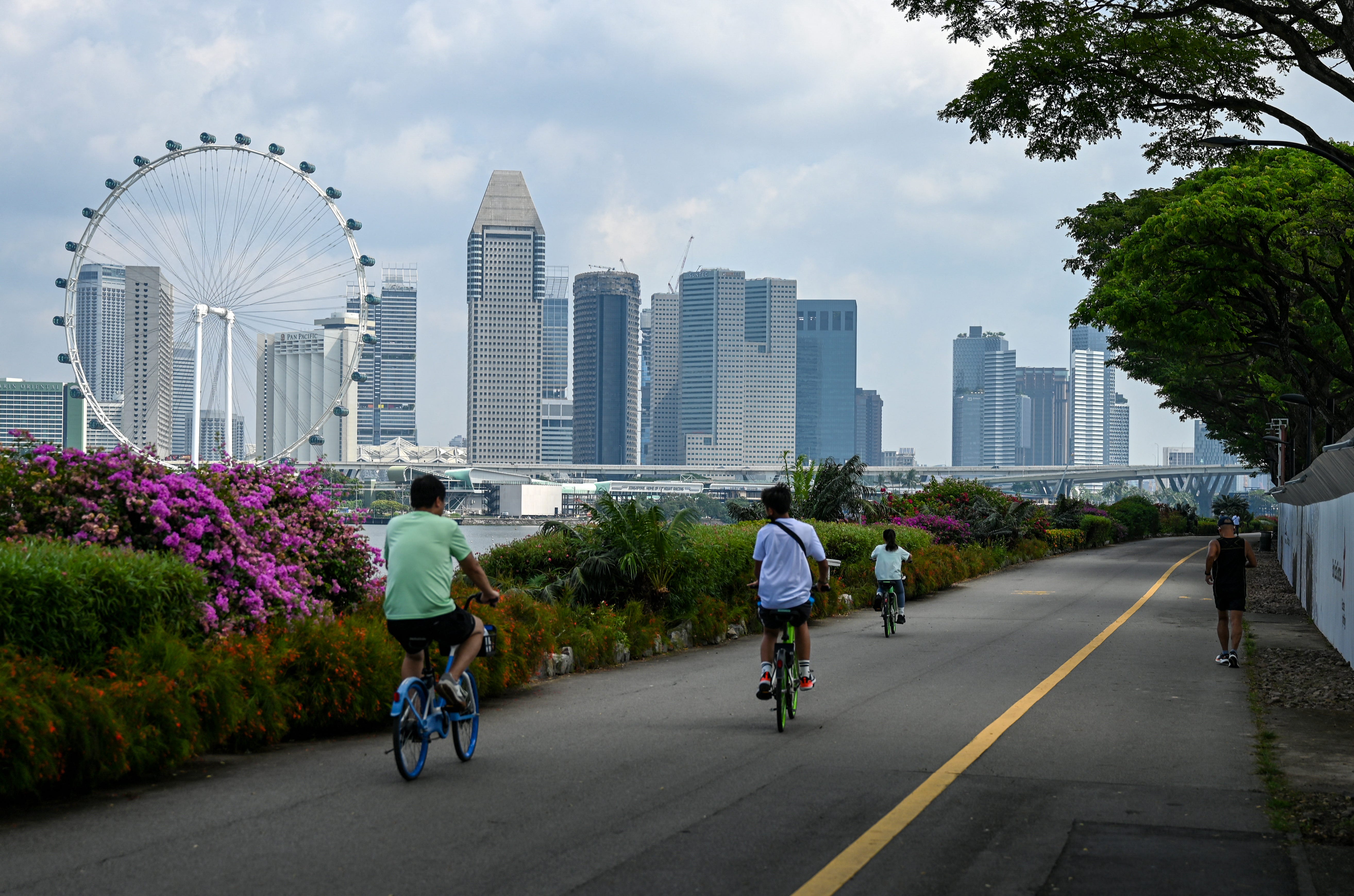 People cycling along a track backdropped with the city skyline in Singapore on June 27, 2025.