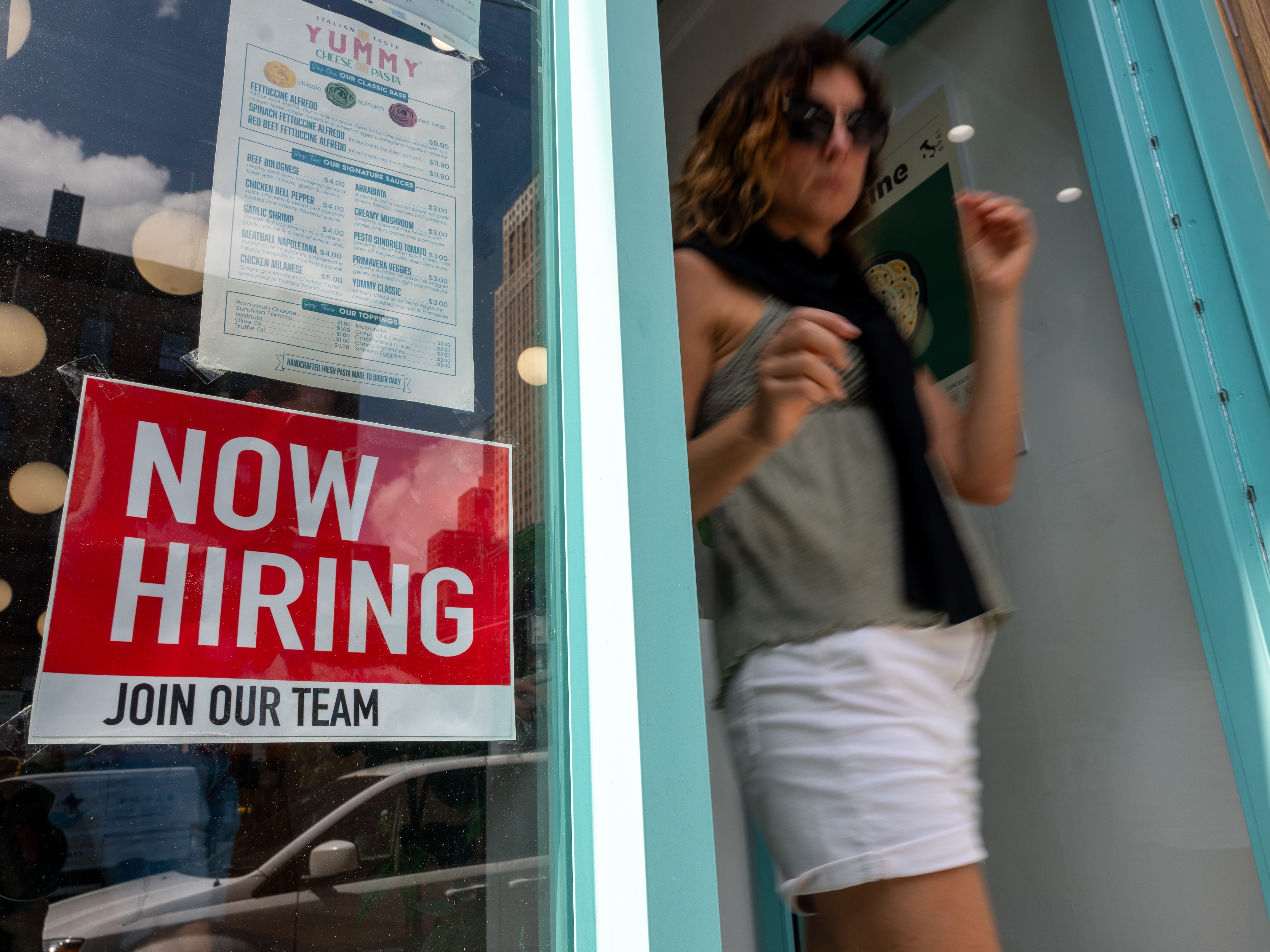 A 'now hiring' sign on a business window
