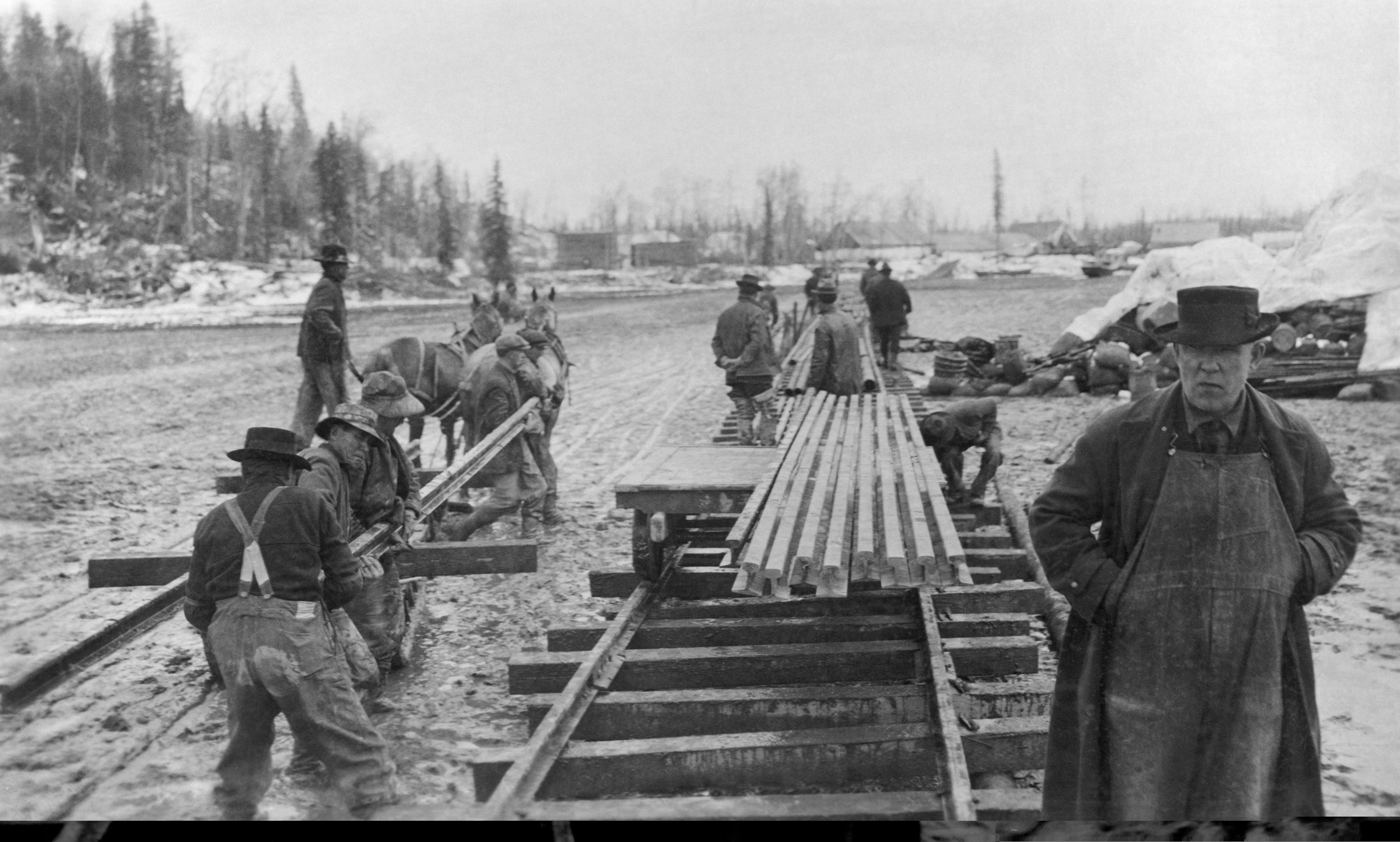 Railroad workers and engineers laying the first rails for a railroad in Alaska.