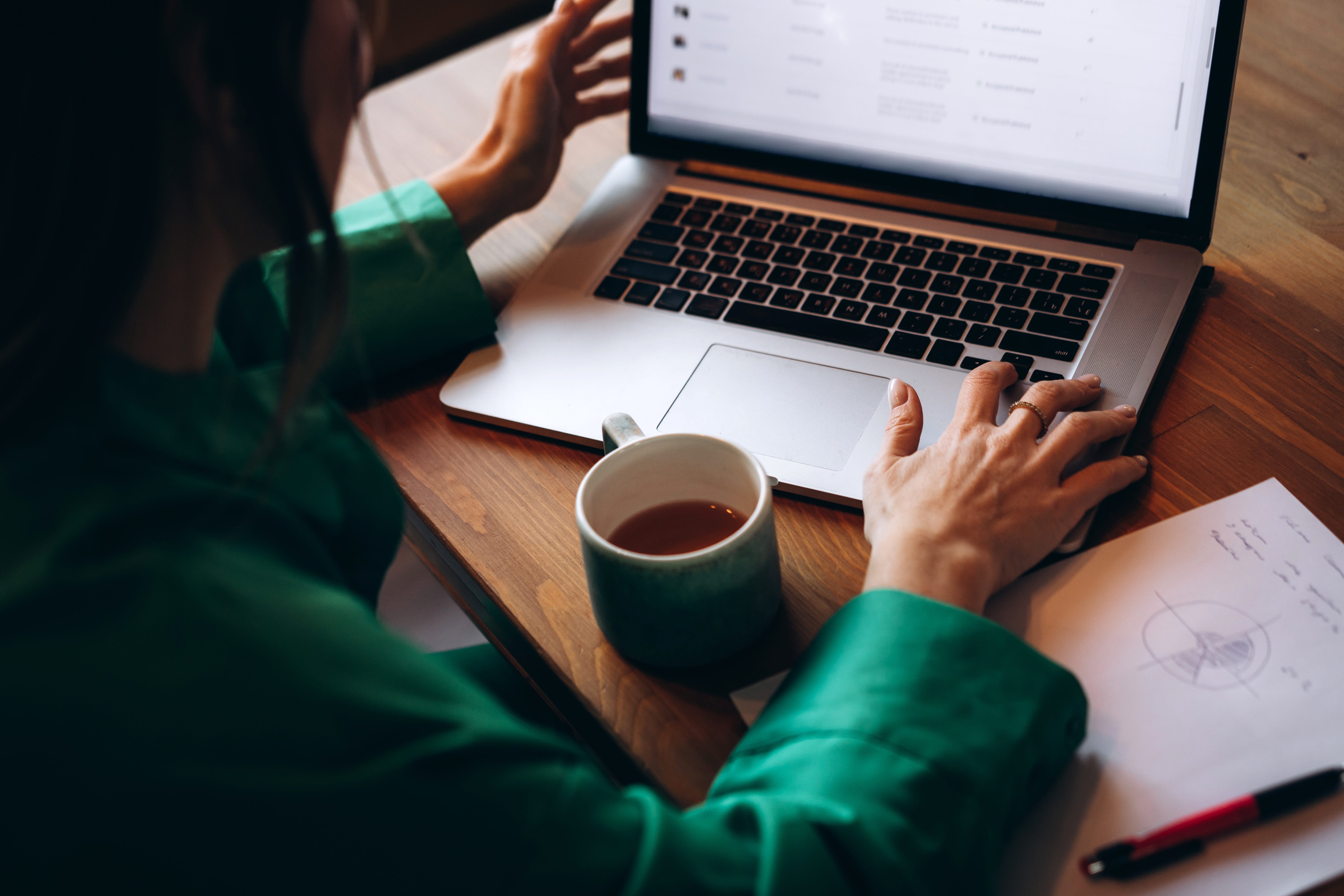 A person works on a laptop with a cup of coffee in front of them