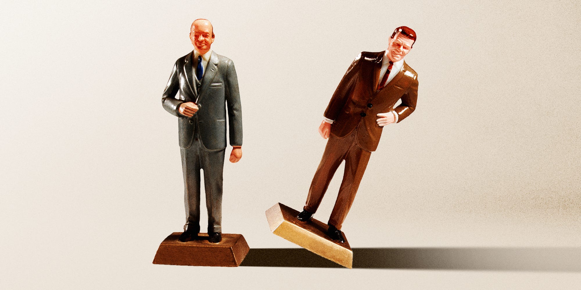 Two business men figures next to one another and on of them tipping over