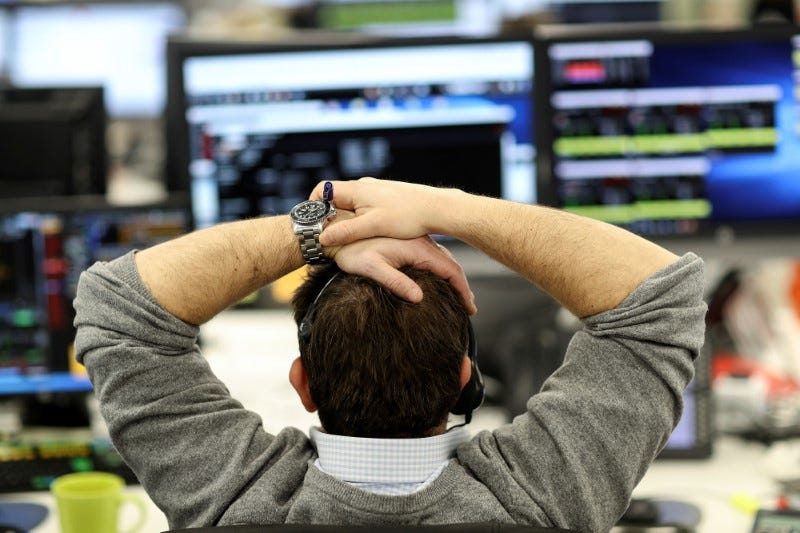 FILE PHOTO: A broker looks at financial information on computer screens on the IG Index trading floor in London, Britain February 6, 2018. REUTERS/Simon Dawson/File Photo
