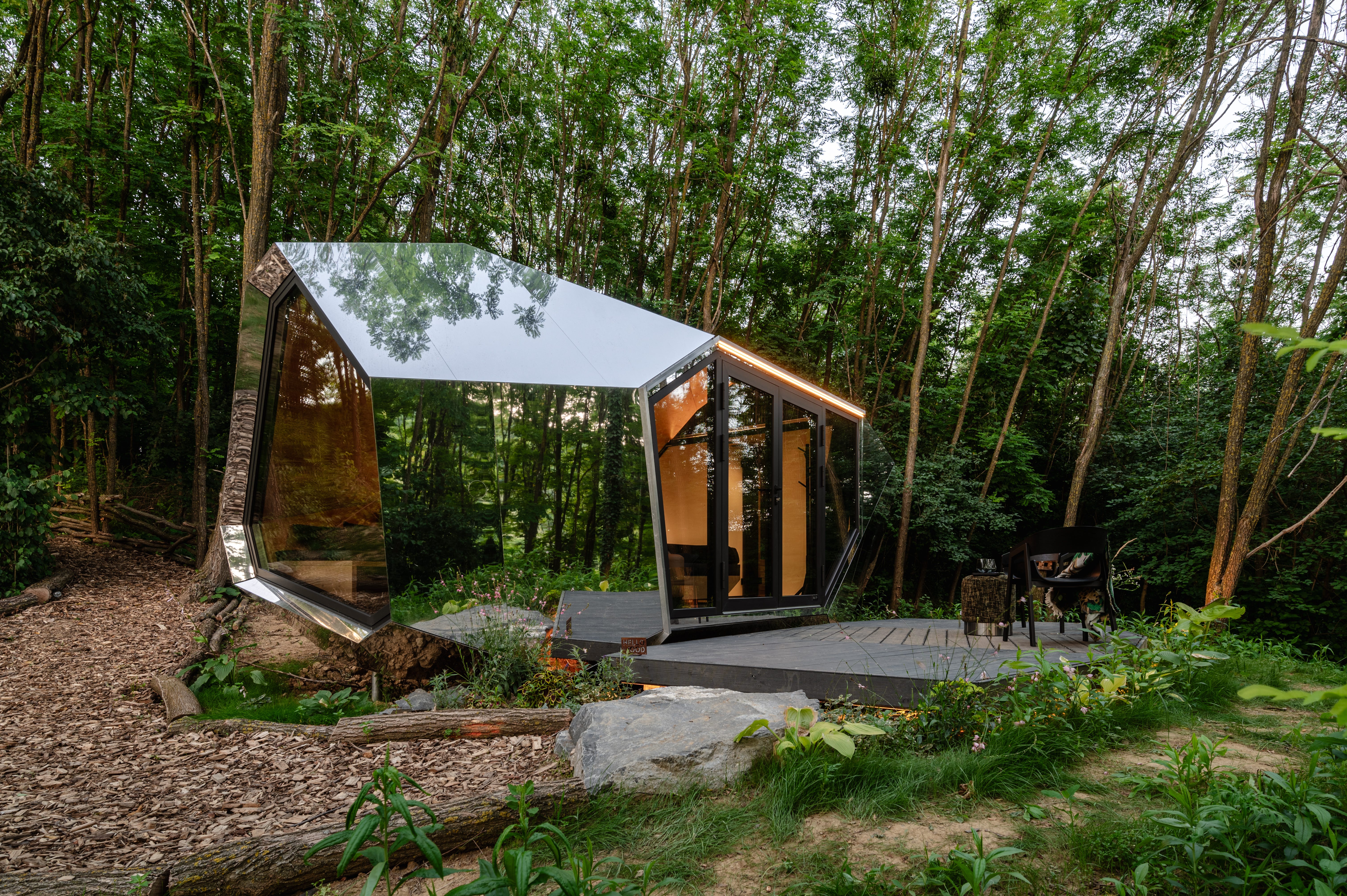 A futuristic, metal tiny home in the center of a forest.