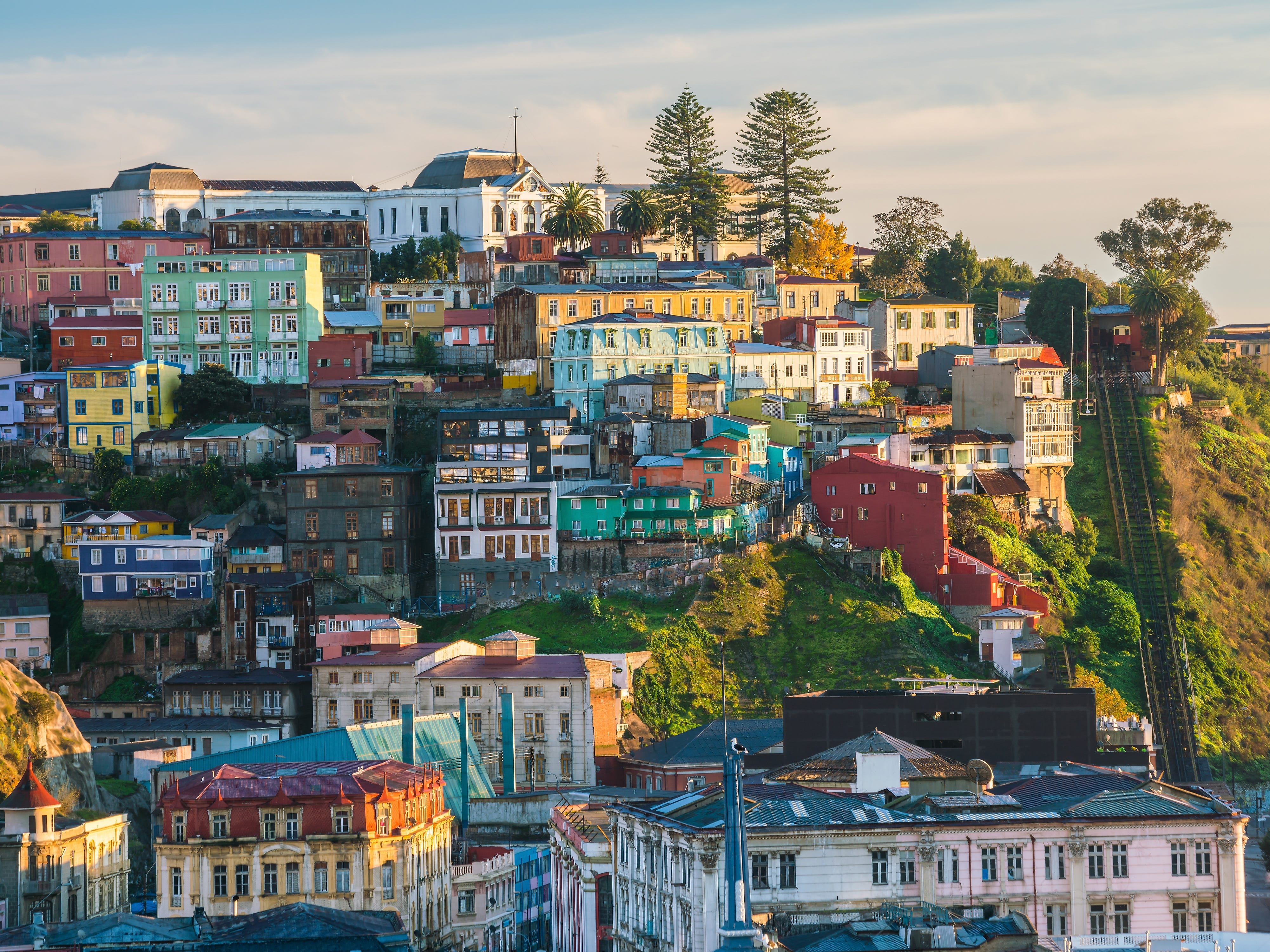 Colorful buildings on a hill, with trees at the top.