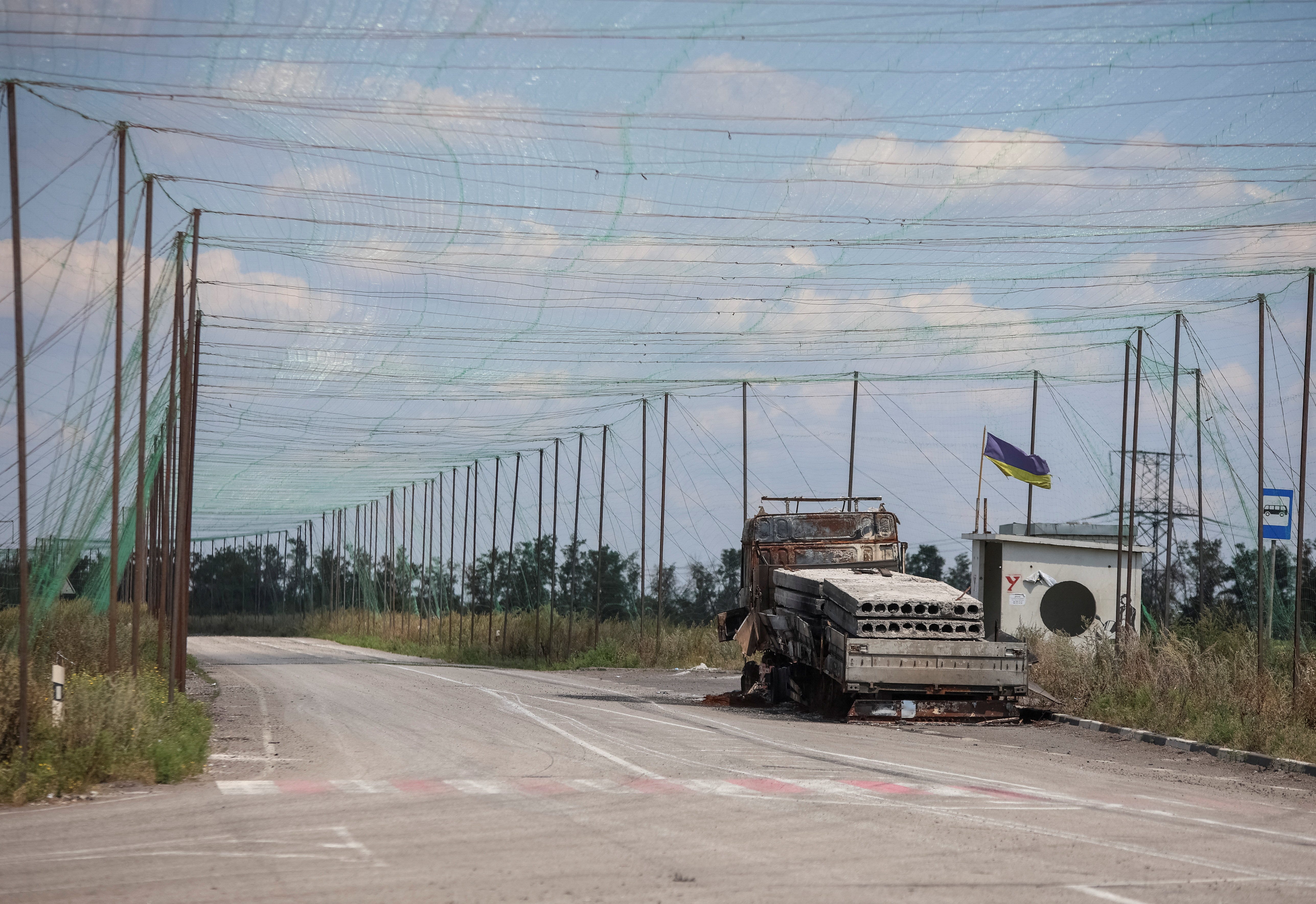 A view shows a burned vehicle and anti-drone nets installed over a road near the frontline town of Dobropillia, amid Russia's attack on Ukraine, in Donetsk region, Ukraine August 10, 2025.