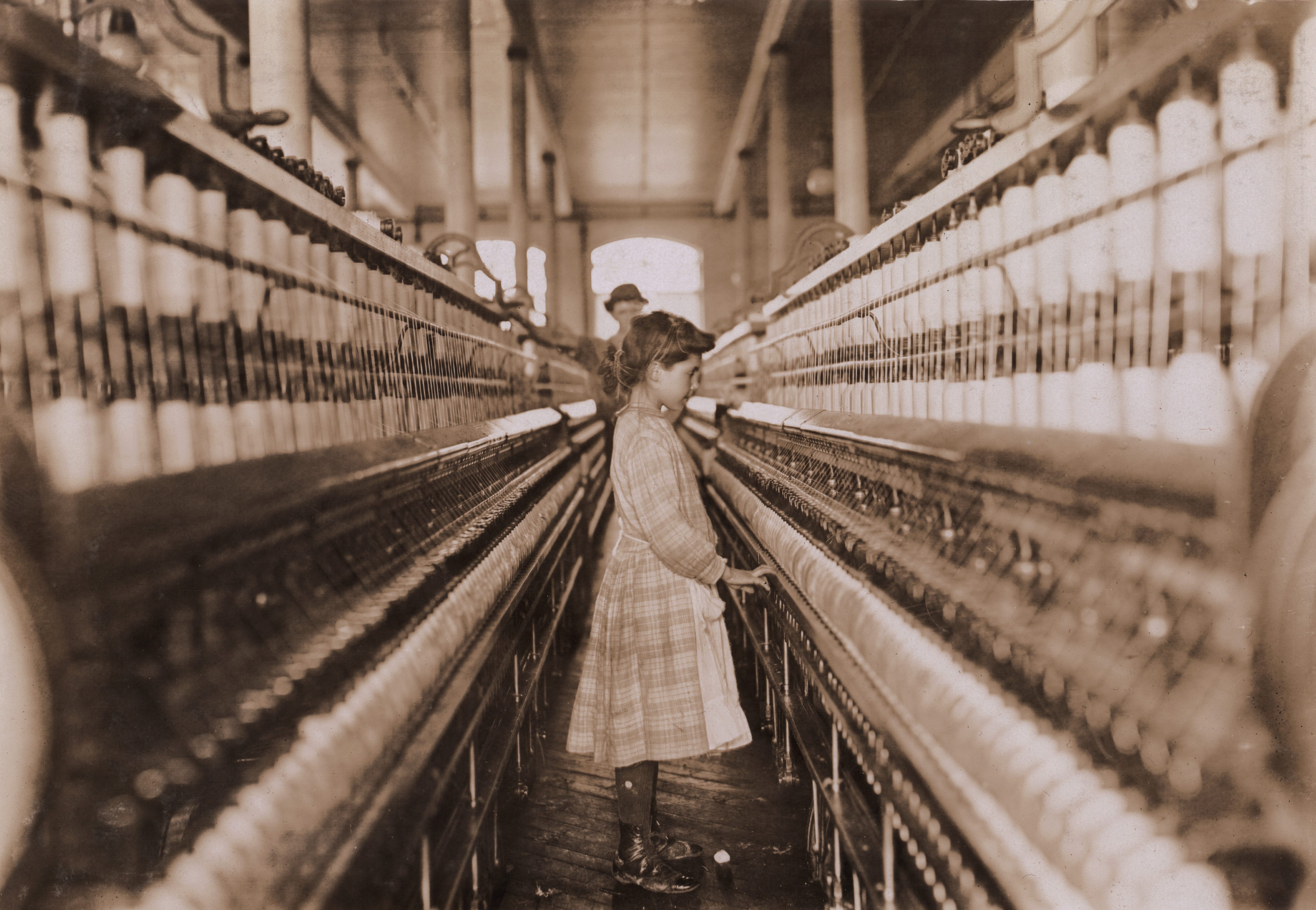 A girl works as a spinner in a mill in the early 1900s.