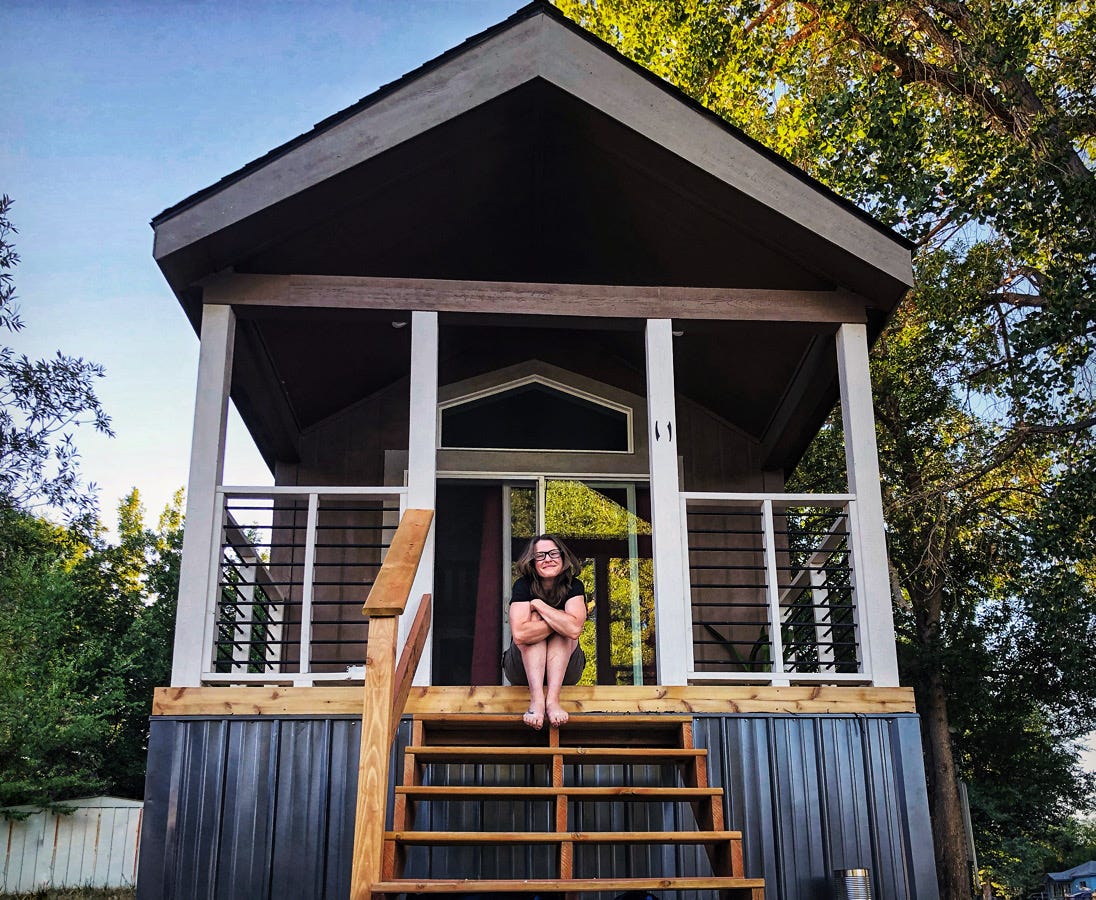 Author Amber McDaniel sitting on steps of tiny home