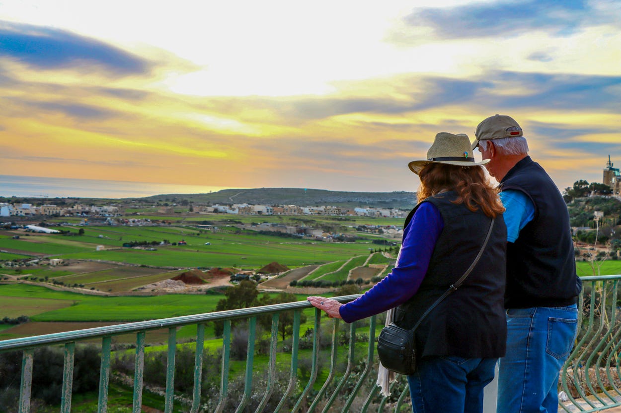 Mary Charlebois and Kevin Scanlon looking at aerial view of Malta on balcony