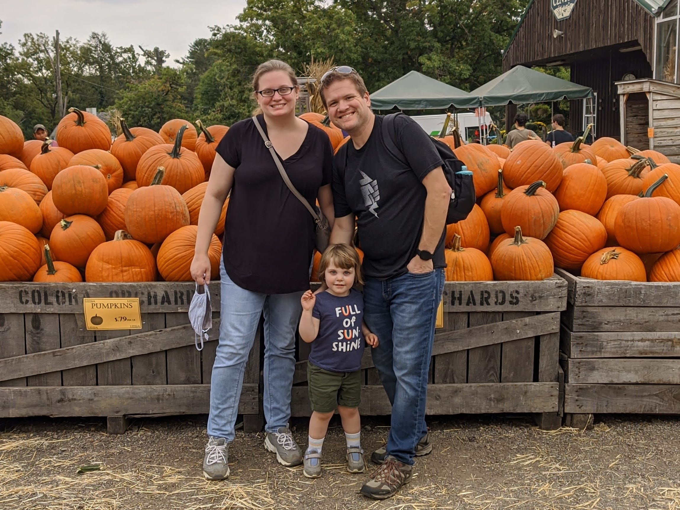 The author with her husband and daughter in front of pumpkins at a pumpkin patch.