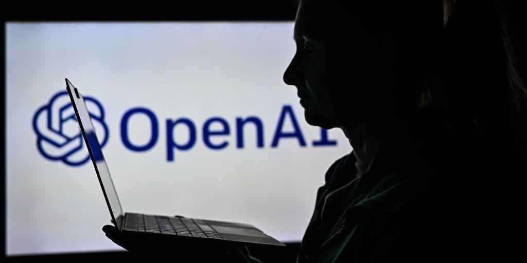 The silhouette of a person holding a laptop next to the OpenAI logo.