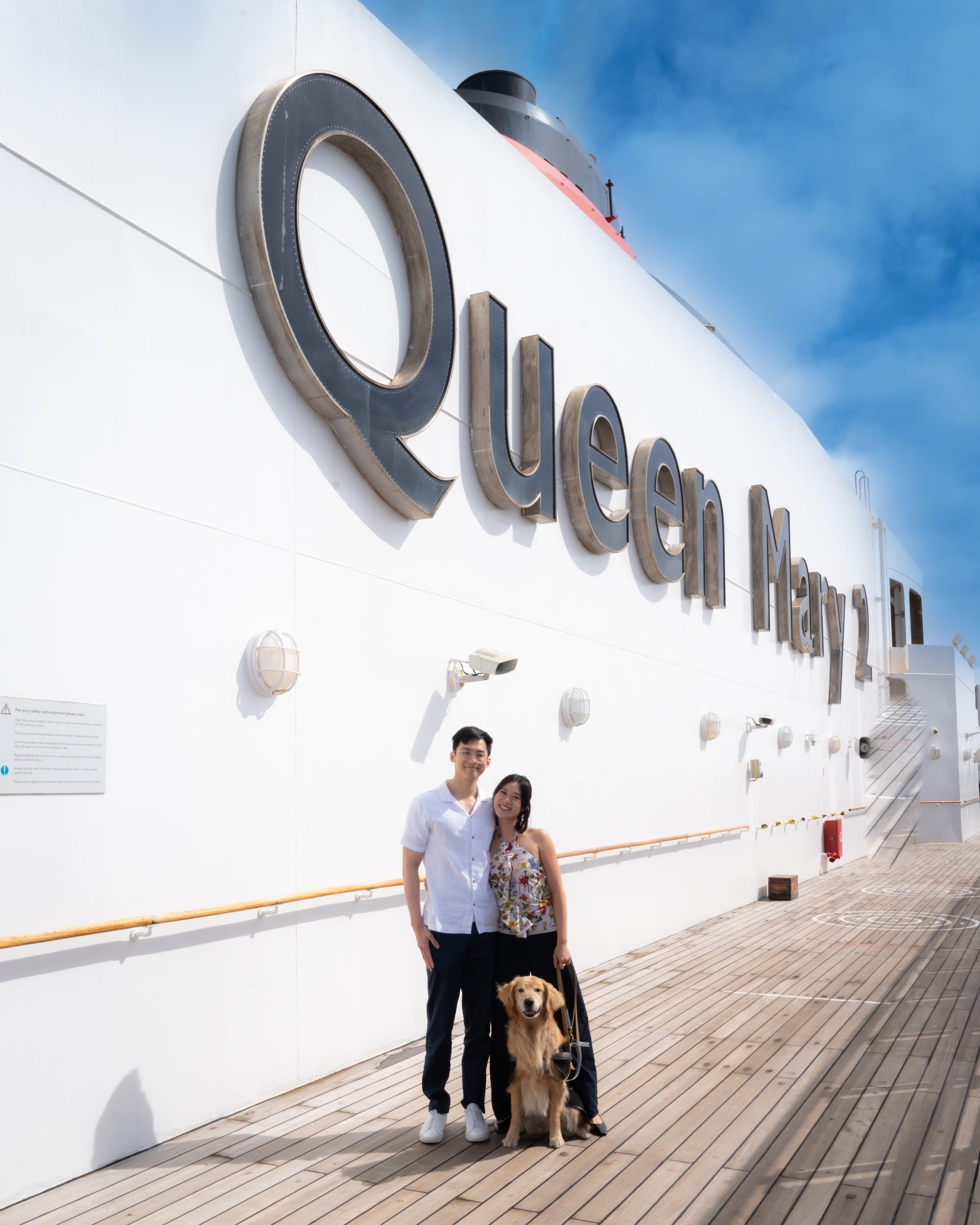 A couple stands on a cruise with their golden retriever. 