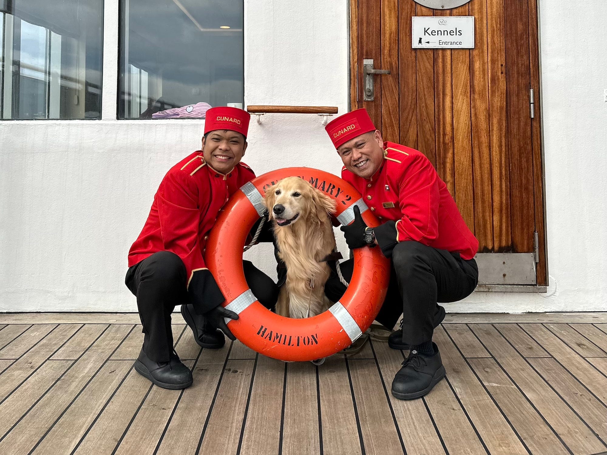 A dog sits inside a pool float as two cruise staffers hold it up for him.