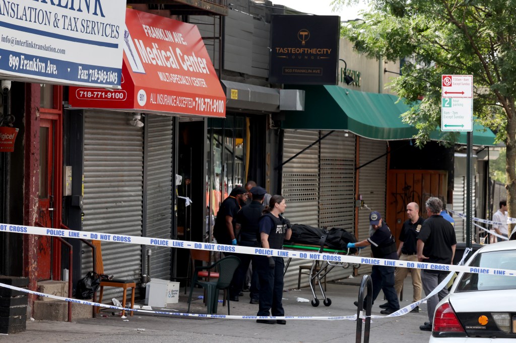 Medical examiner technicians remove a body from Taste of the City Lounge after a mass shooting.