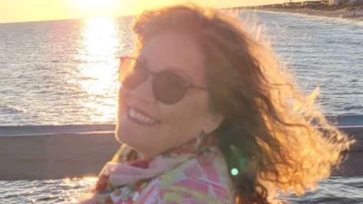 Joy Rogers, 64, smiling with the sun behind her.