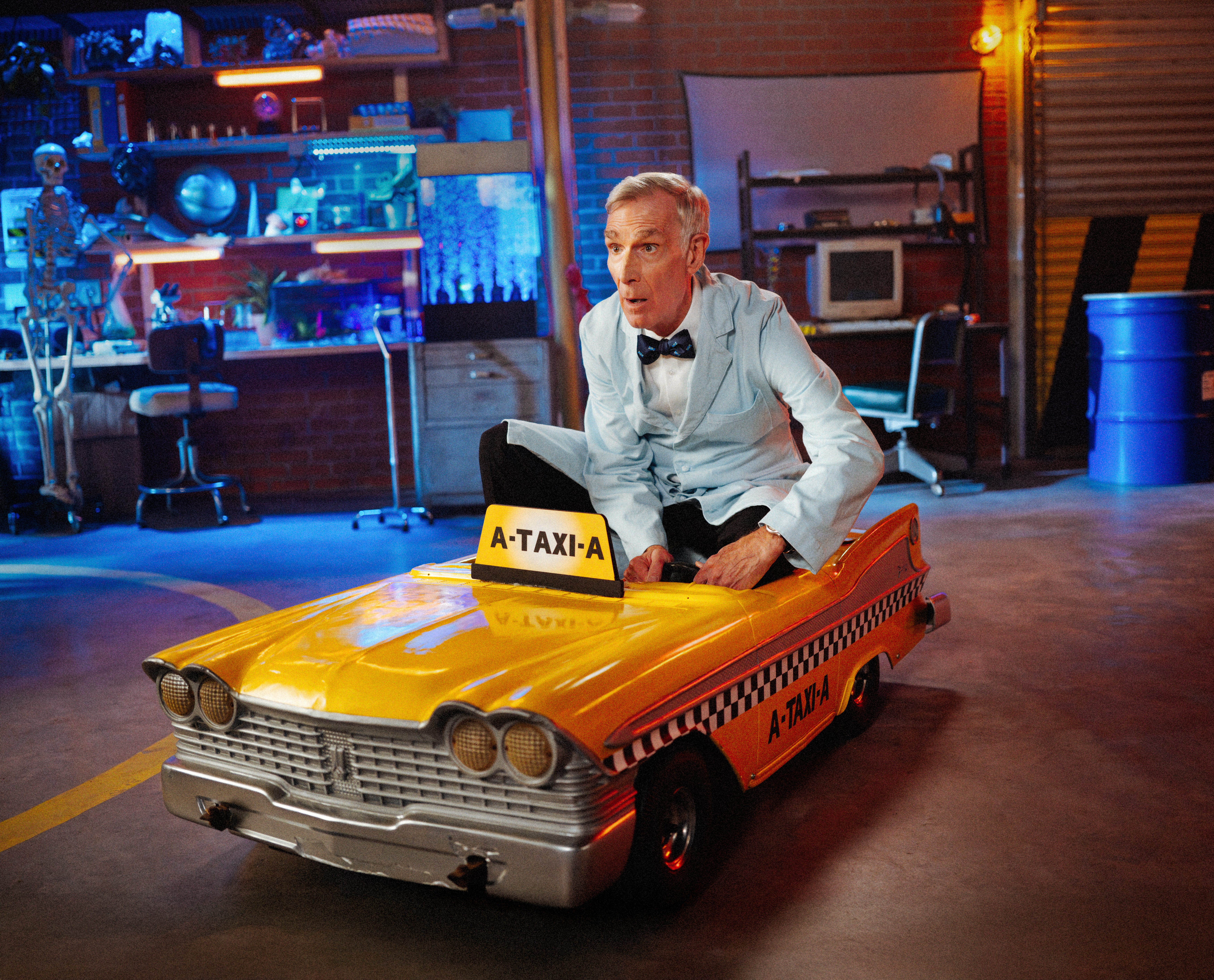 Bill Nye in a small taxi cab