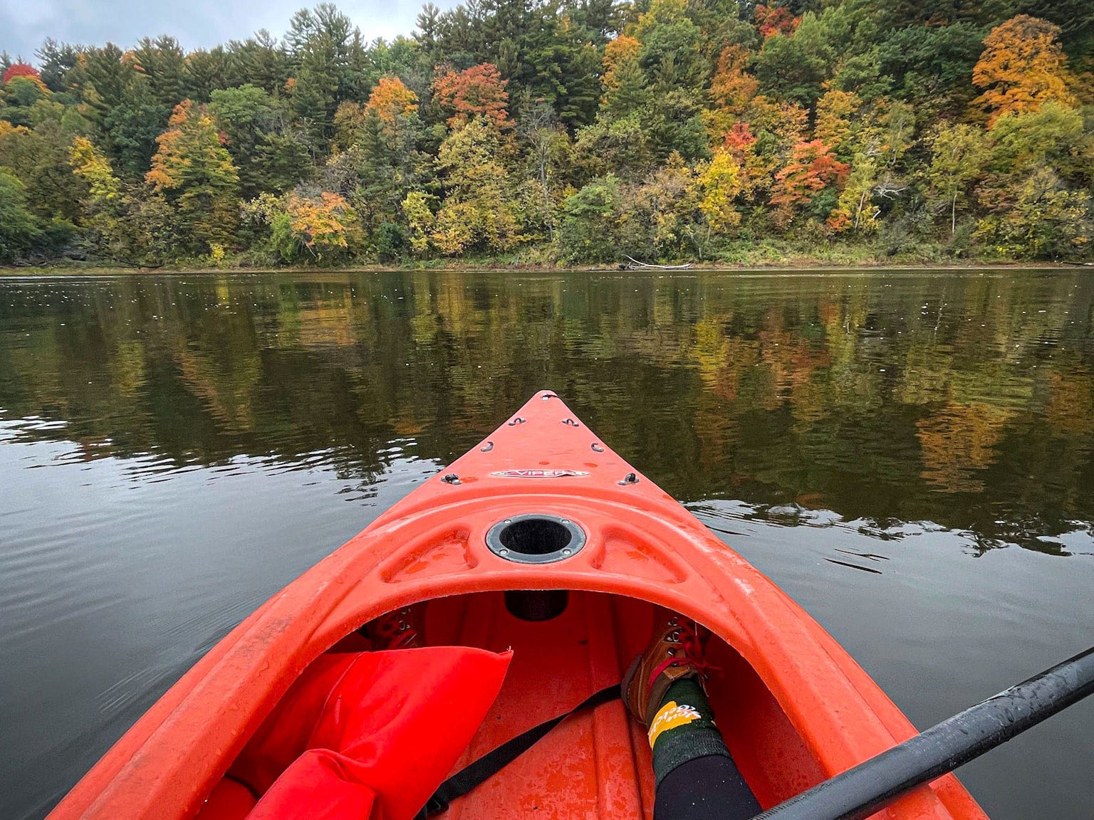 A kayak in a lake surrounded by fall foliage.