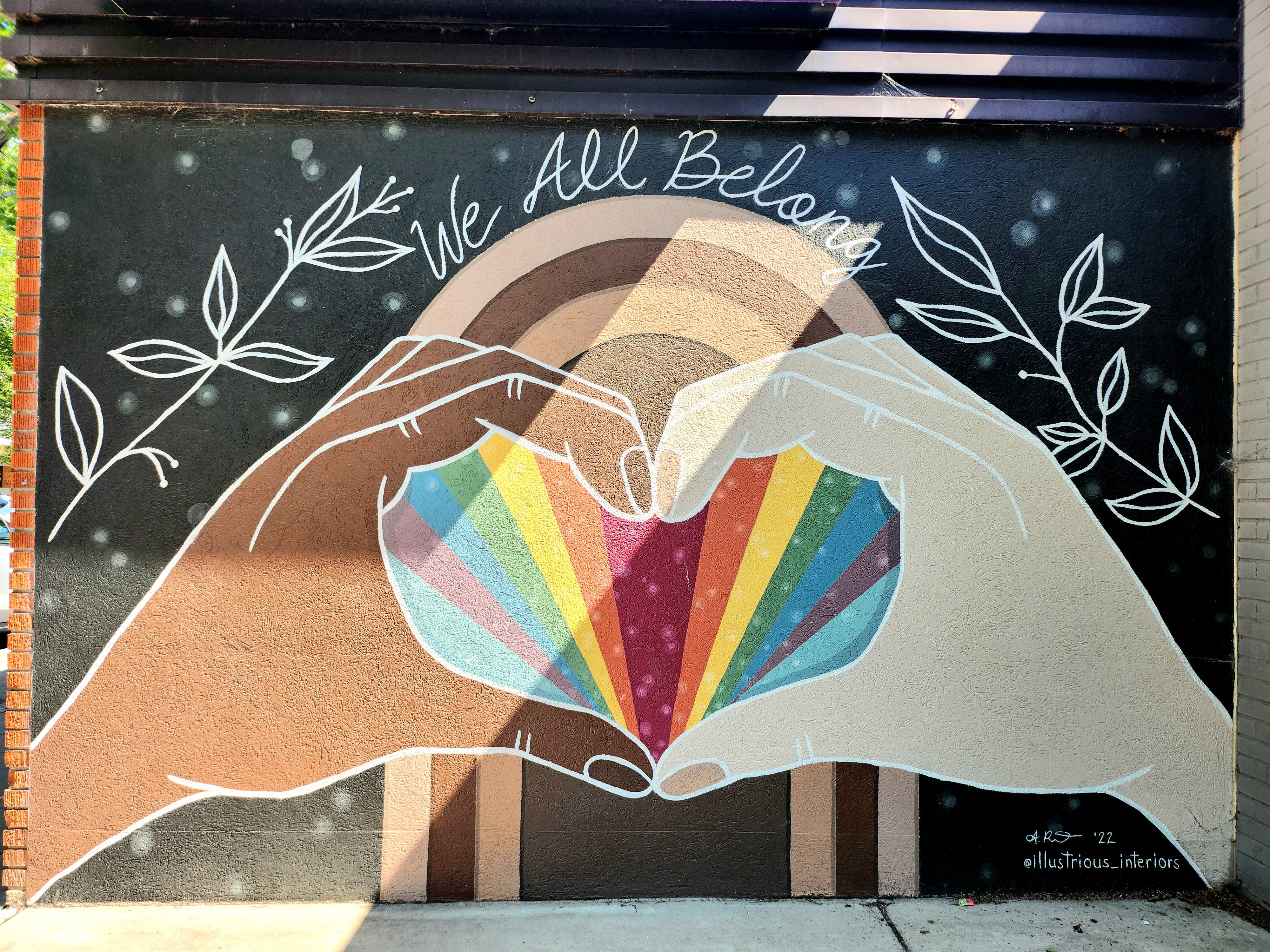 Mural with brown hand and white hand forming heart with rainbow in the middle