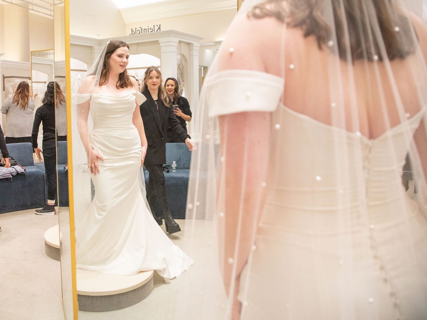 A woman in a wedding dress looks at herself in a mirror.