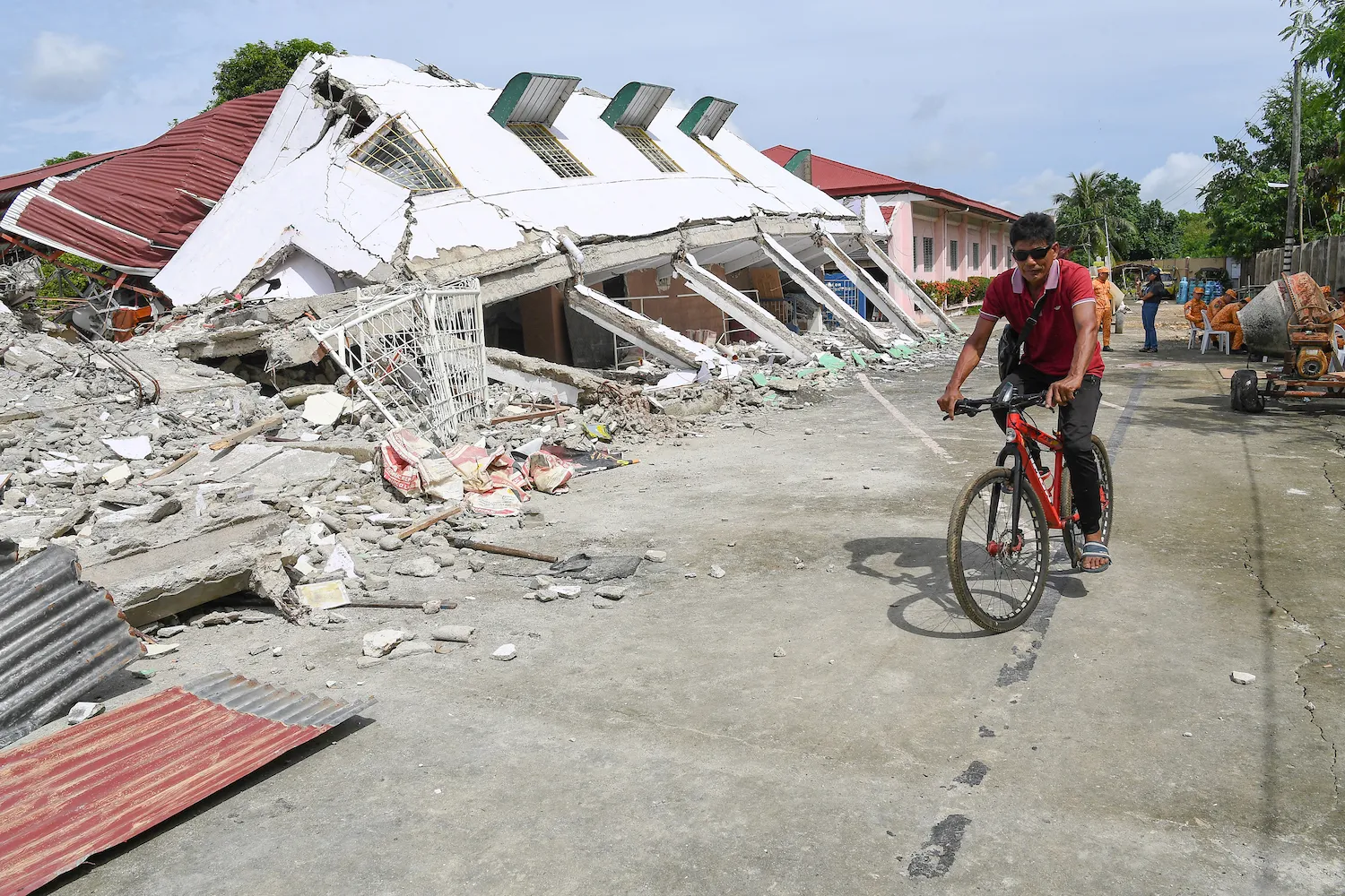 A man rides a bicycle past a collapsed building where three missing people were found dead among the rubble in Bogo City, Cebu province, on Oct. 2, in the aftermath of a 6.9 magnitude earthquake that struck off the coast of the central Philippines on Sept. 30.