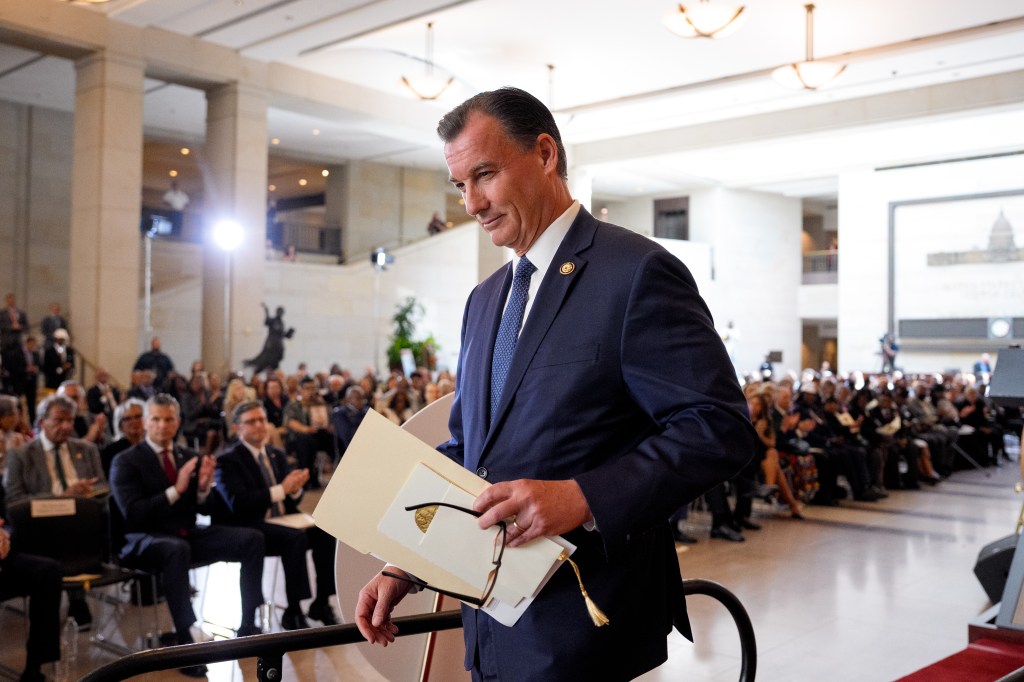 Rep. Tom Suozzi walking off stage at a Congressional Gold Medal ceremony.