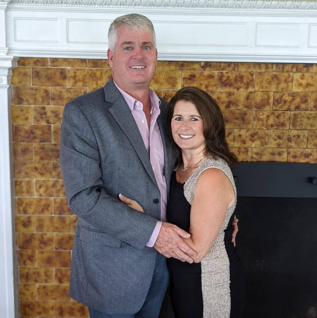 Linda Murphy and a man posing in front of a fireplace.