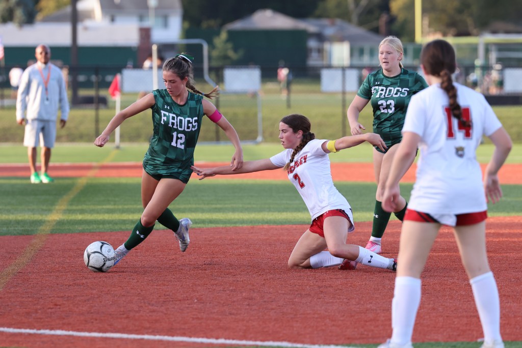 Madison Reedy dribbles a soccer ball past an opponent for the Frogs during a game.