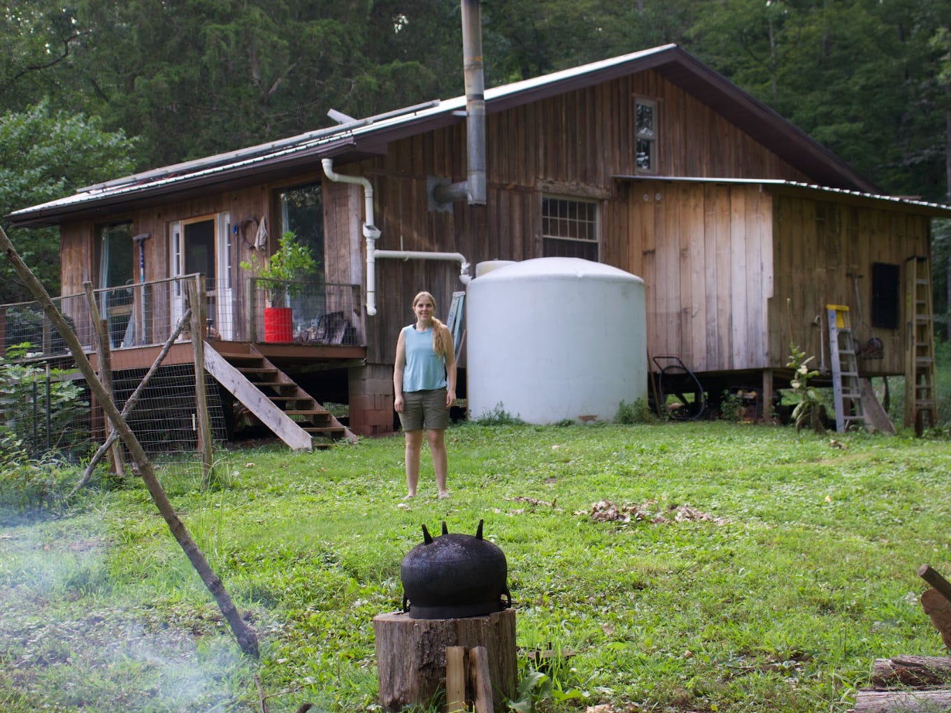 The writer standing in front of her off-grid cabin.