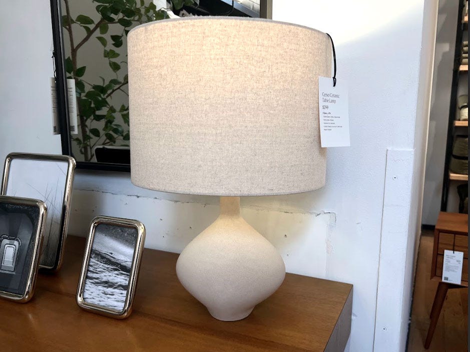 A lamp on a table with small picture frames.