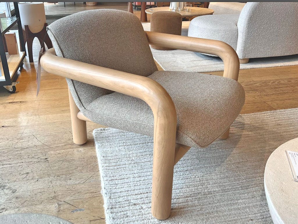 A gray chair with thick wooden arms and legs.