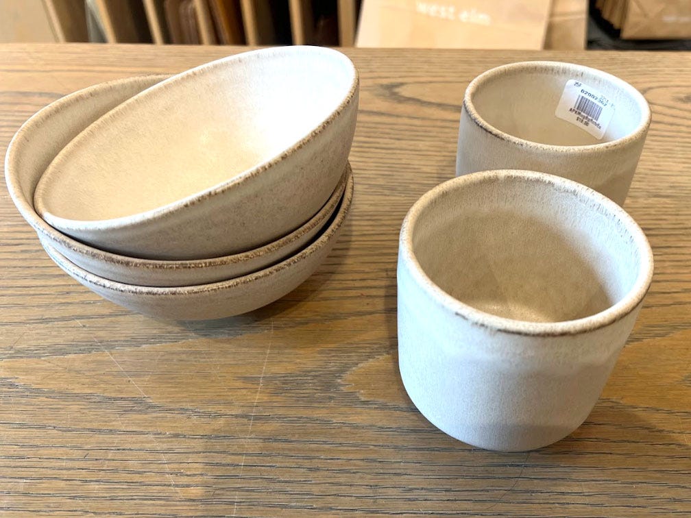 A stack of three bowls and two mugs on a table.