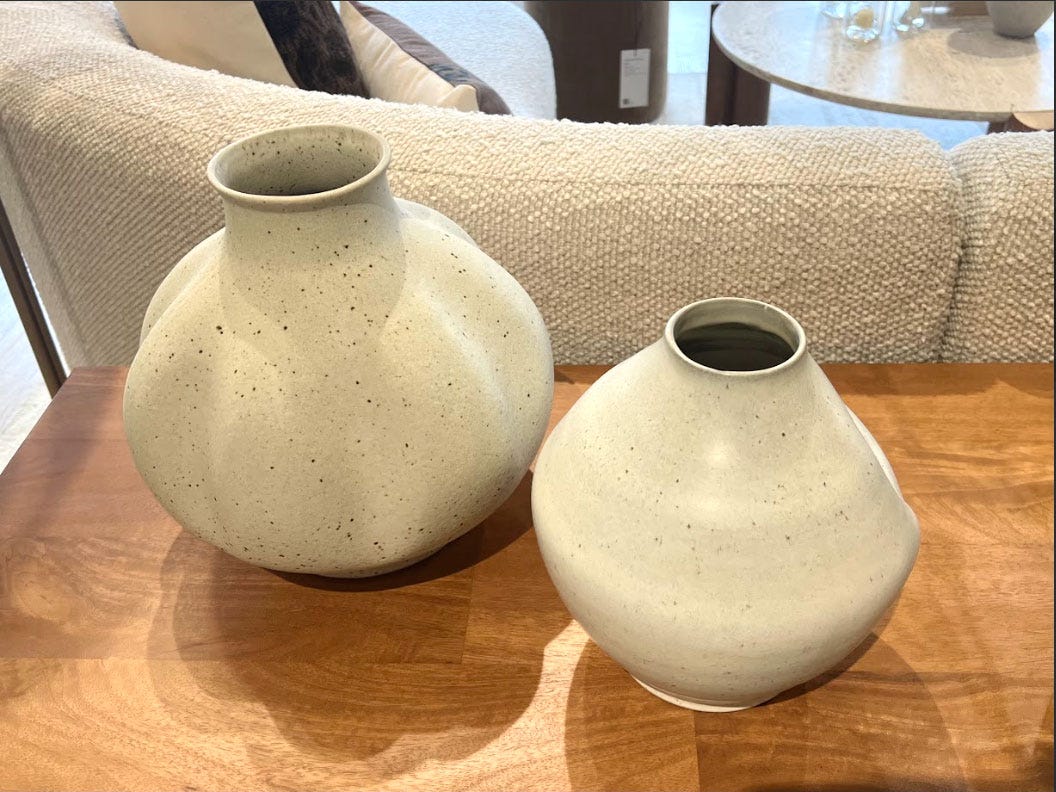 Two cream-colored vases in different sizes.
