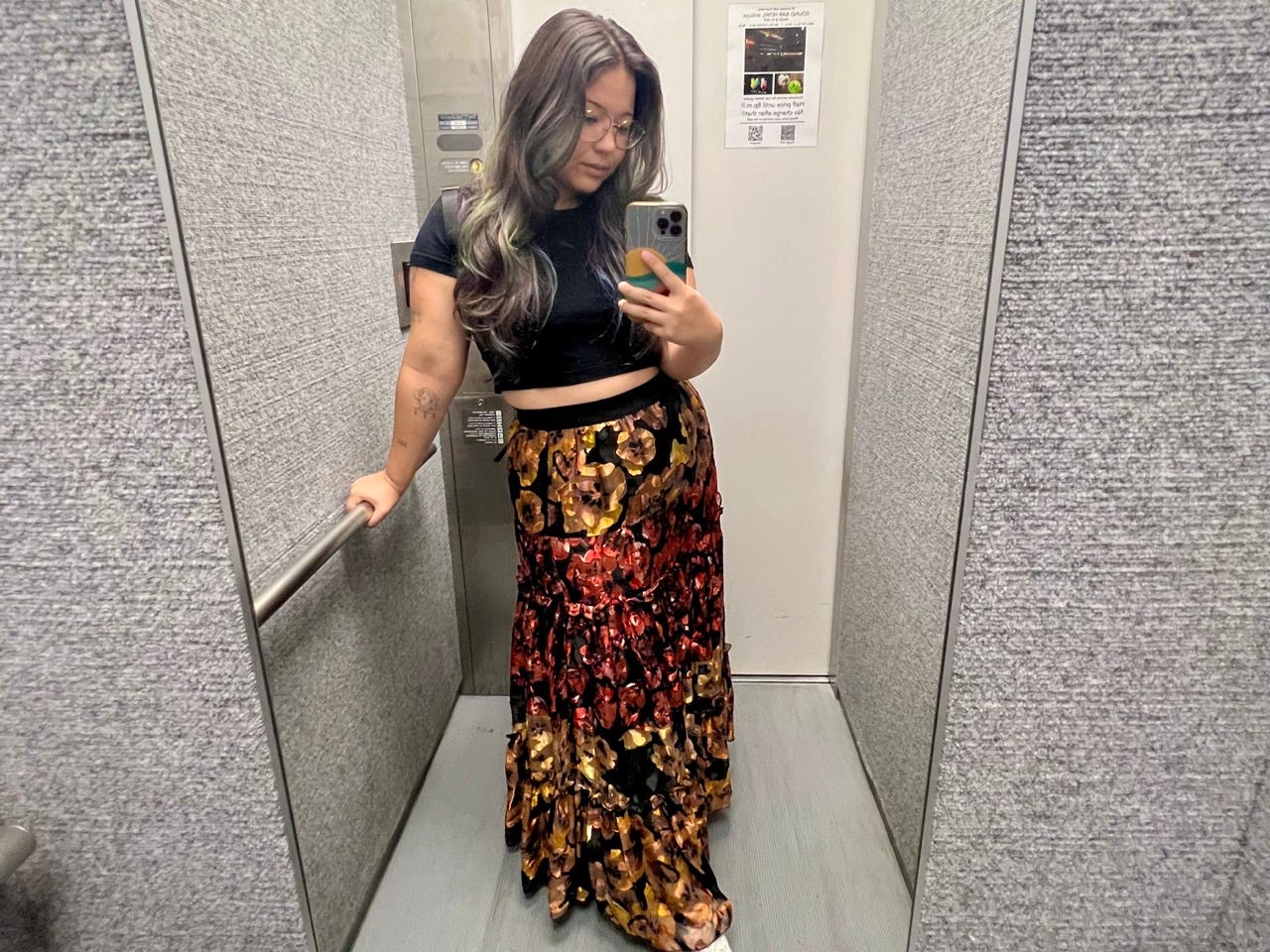 Author Ashley Probst taking mirror selfie in elevator wearing colorful skirt
