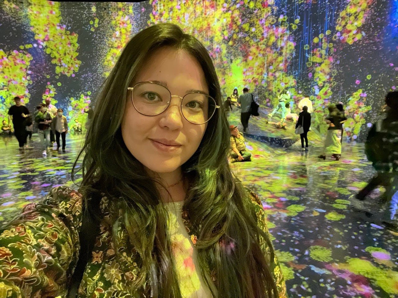 Author Ashley Probst smiling inside exhibit with colorful lights