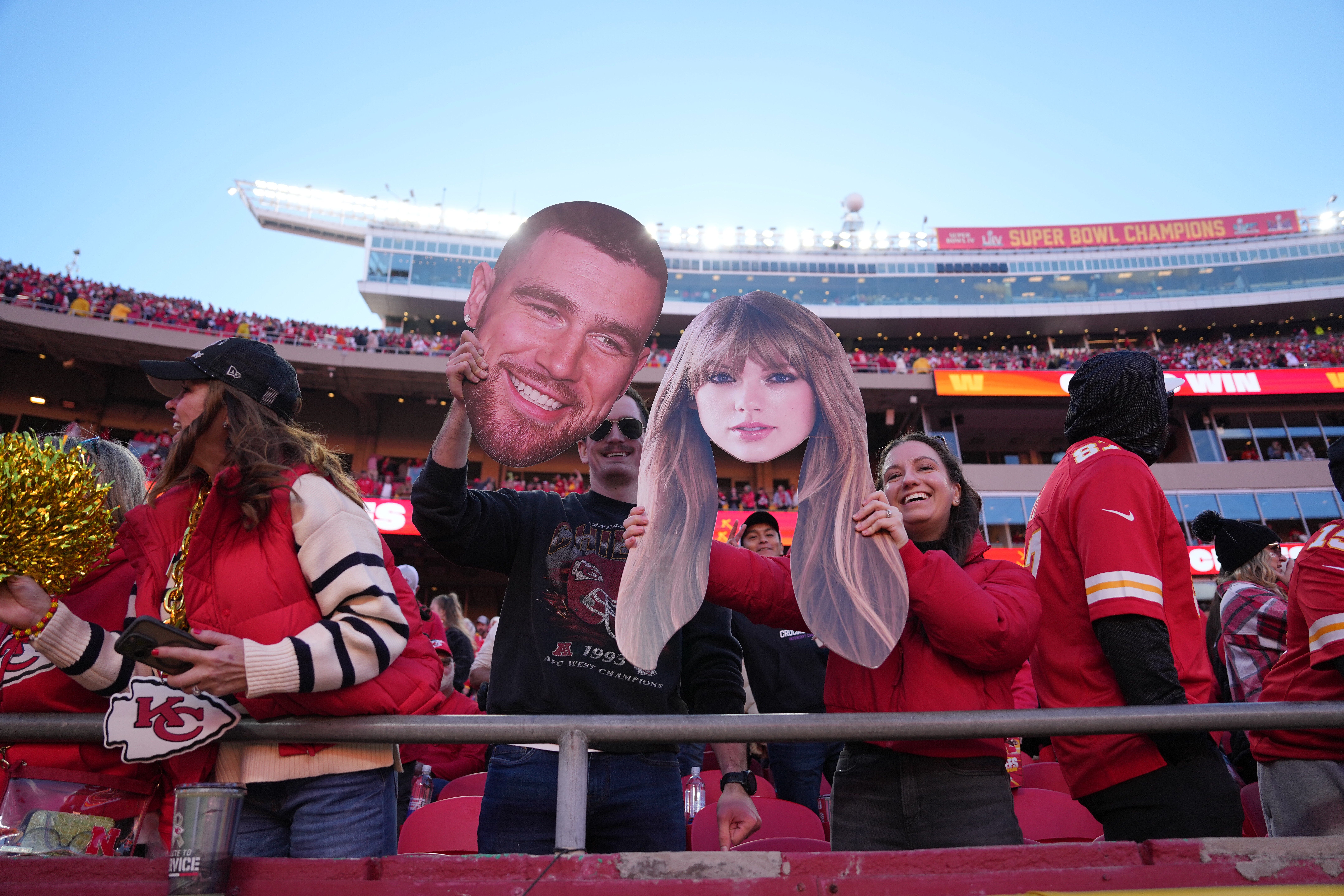 Fans hold cutouts of Travis Kelce and Taylor Swift's heads at a Chiefs game in 2024.