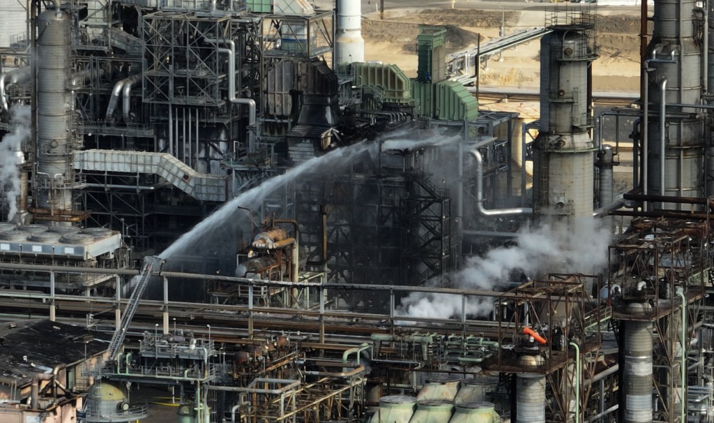 Fire crews spray water on a burned portion of Chevron's El Segundo refinery.