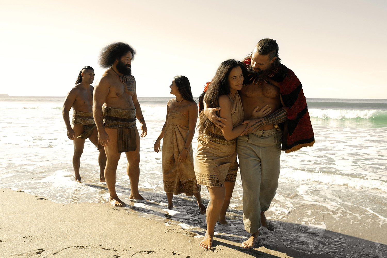People walk along the beach in a tv show still.