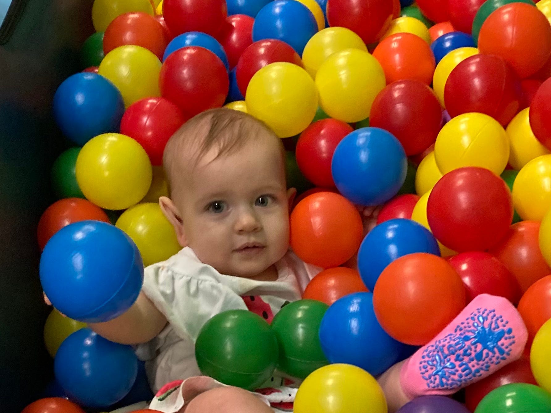 Toddler sits in ball pit