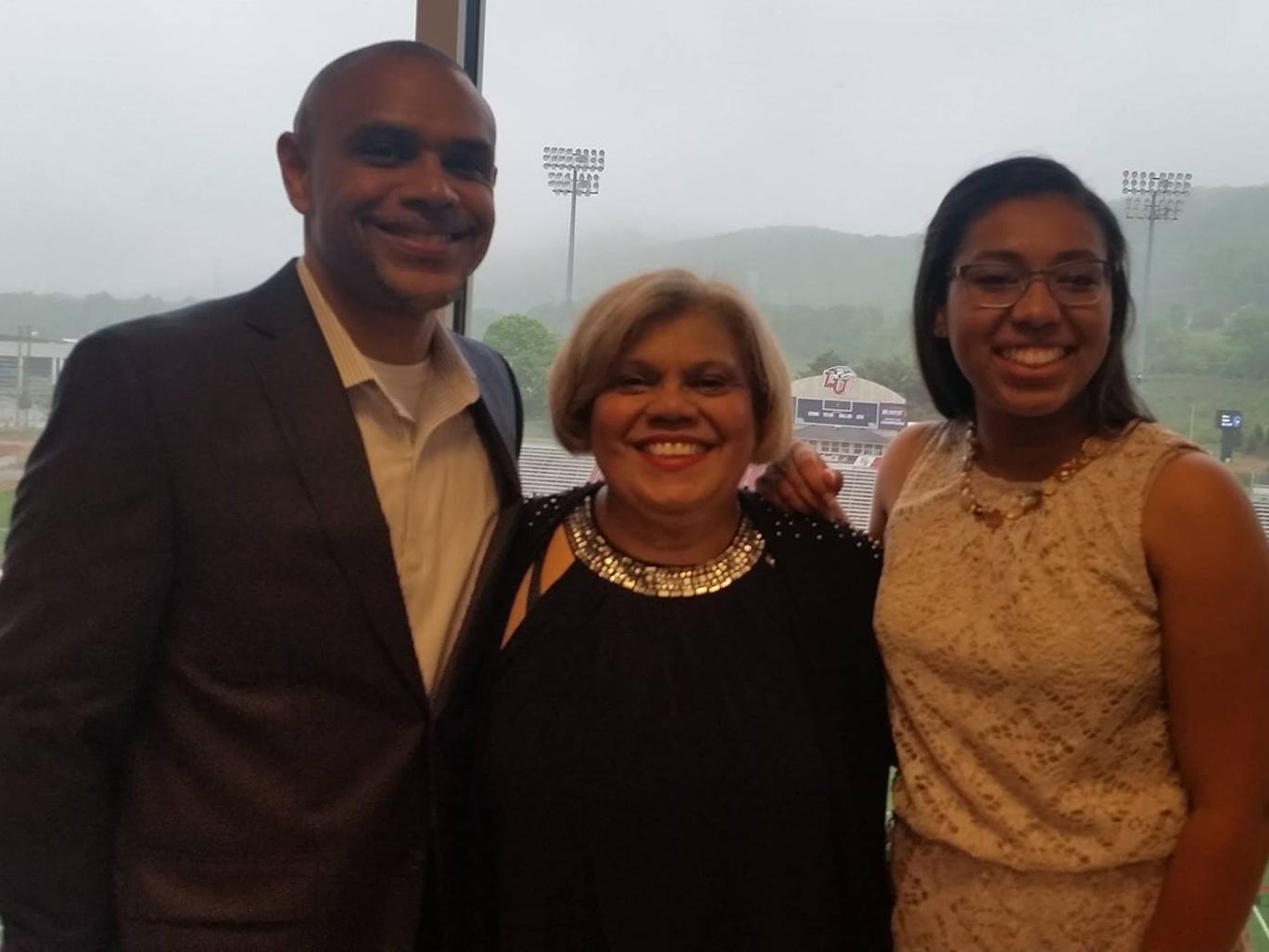 Juan Cruz Jr. with this mother and daughter in front of a football field at graduation