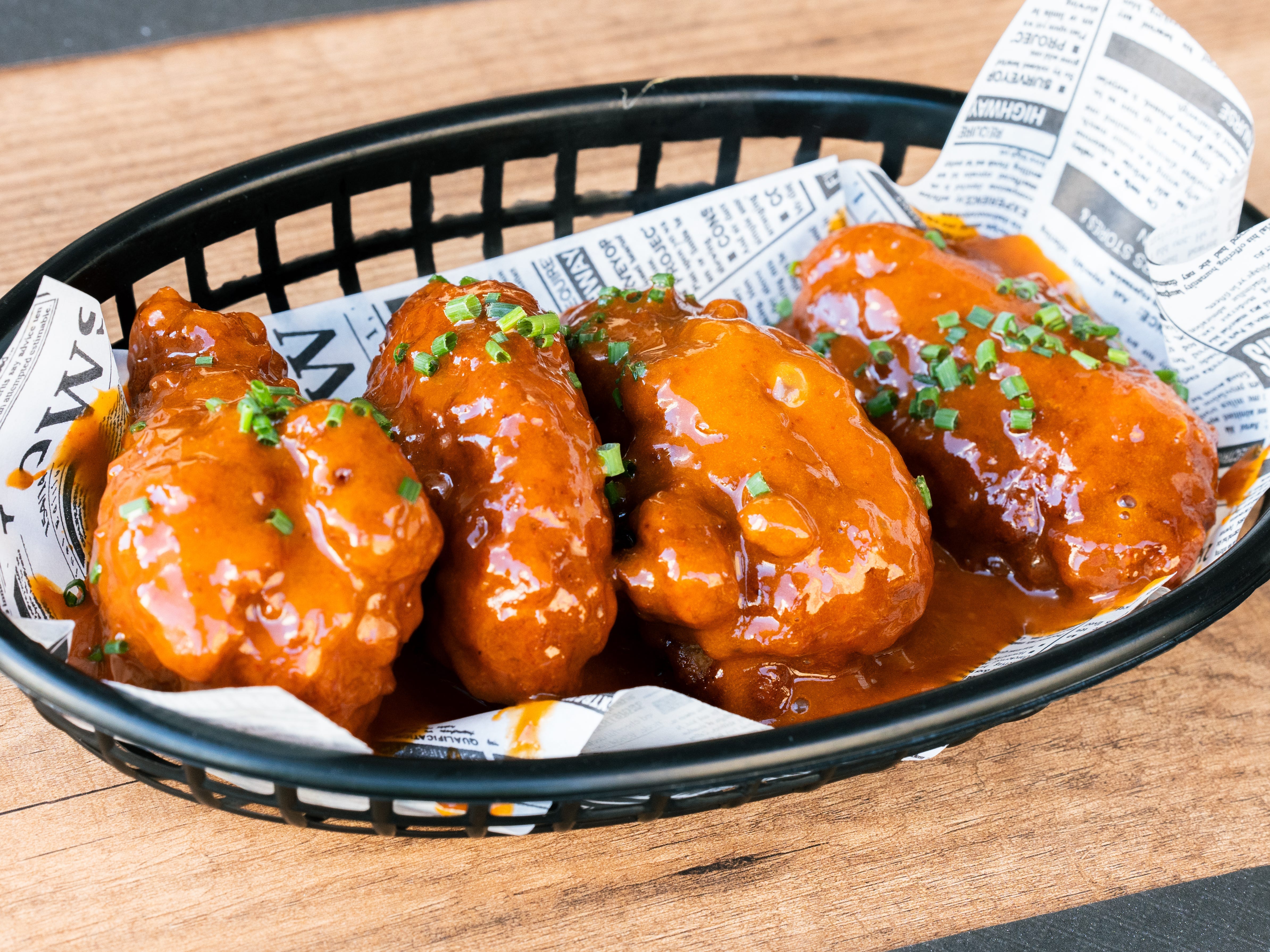 A basket of chicken wings with sauce.