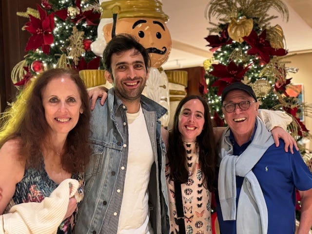 A family of four standing in front of holiday decorations