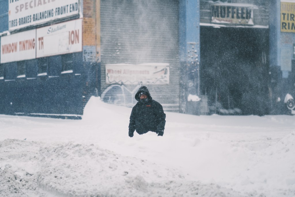 An auto worker wearing a hooded coat in the Iron Triangle in Flushing, Queens, during a snowstorm on Jan. 29, 2022