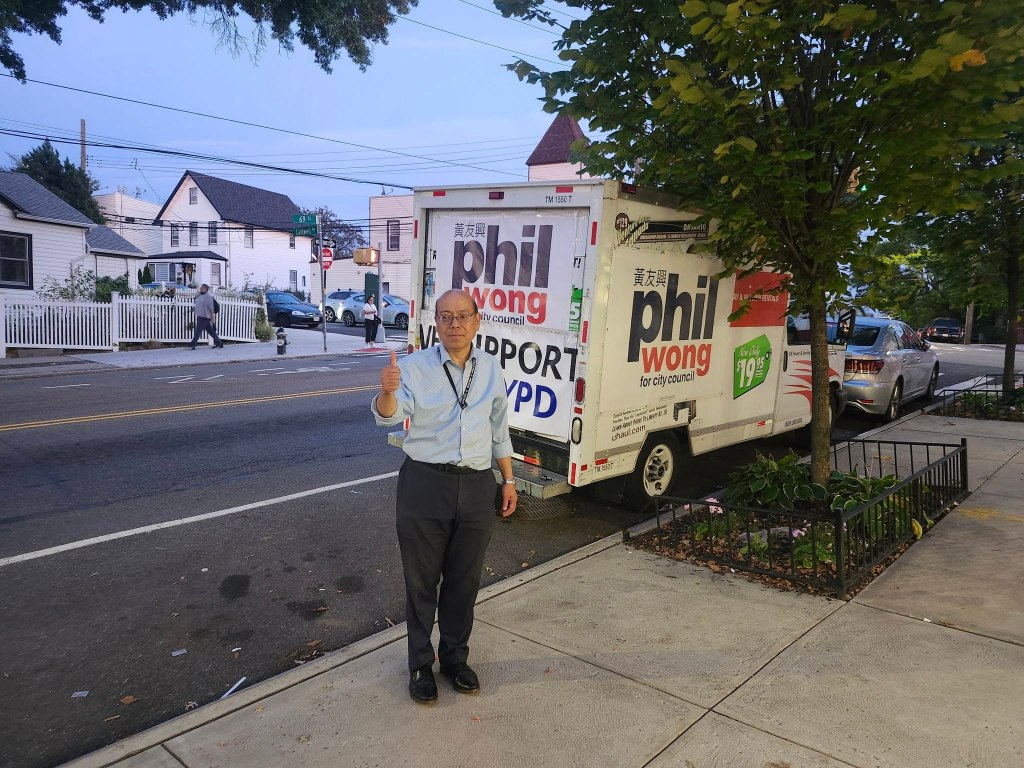 Phil Wong, a Democratic candidate for City Council in Queens, stands next to a U-Haul truck covered with his campaign posters.
