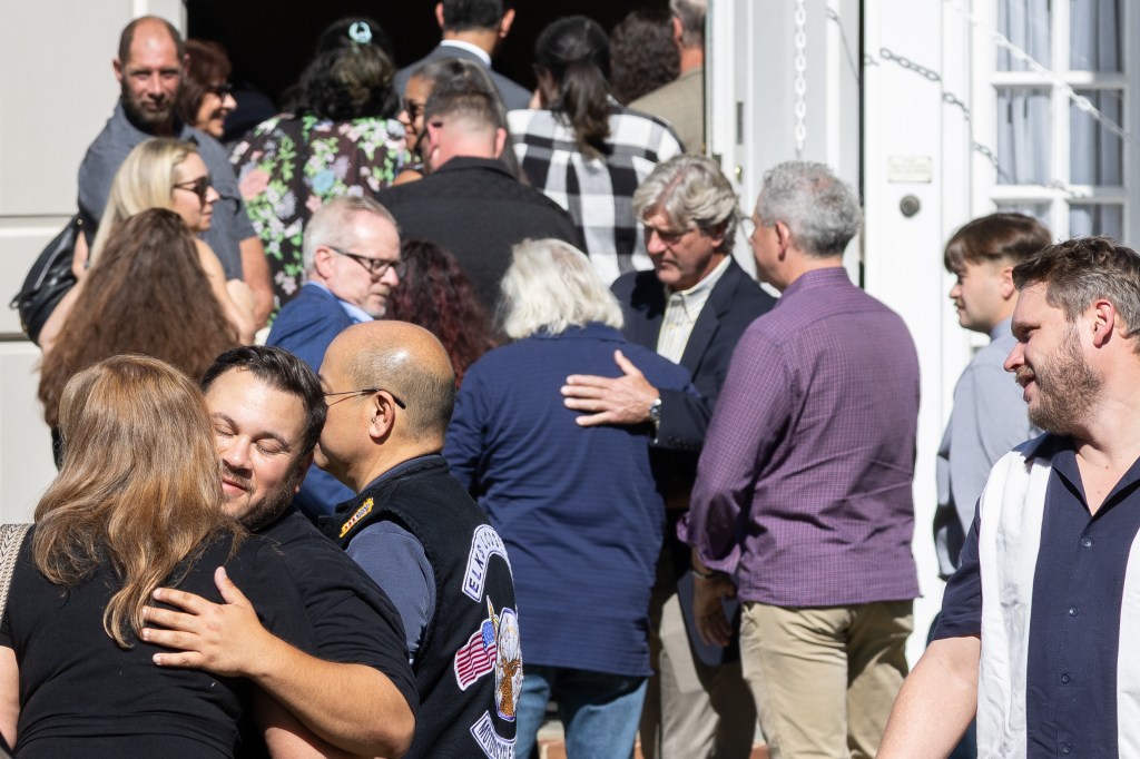 crowd comforts each other outside funeral home