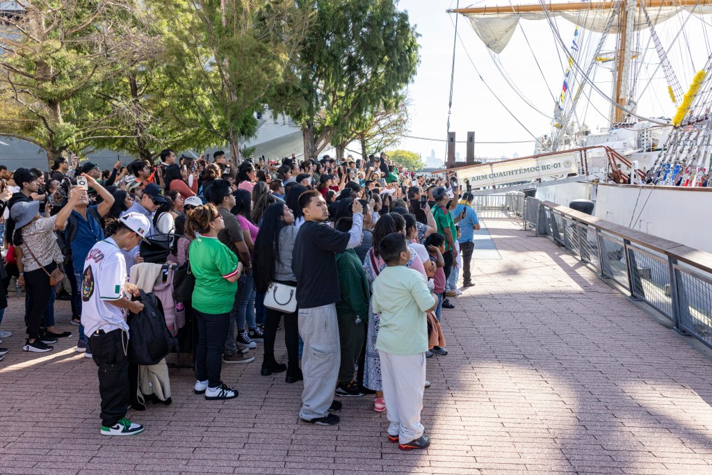 Crowds gather on the pier near the Intrepid to see off the repaired Cuauhtémoc.