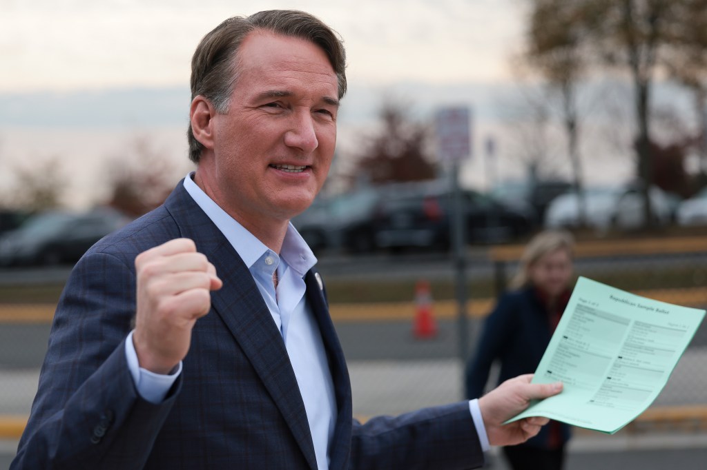 Virginia Governor Glenn Youngkin gestures to supporters while holding a Republican Sample Ballot.