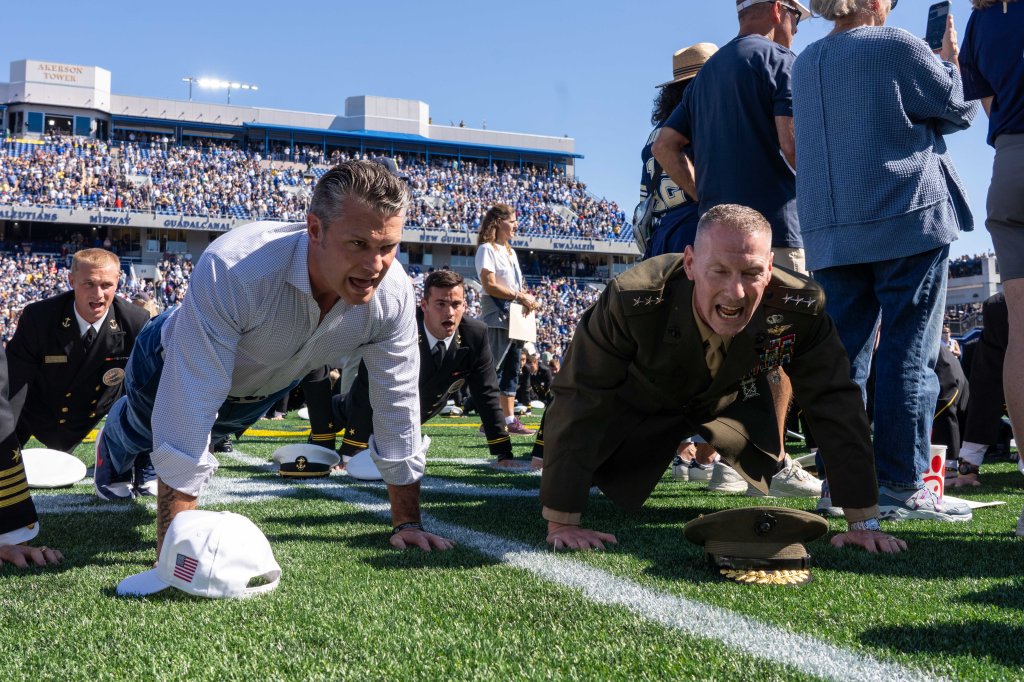 Secretary of War Pete Hegseth and Marine Corps Lieutenant General Michael J. Borgschulte participating in a push-up world record attempt at the Navy vs. Air Force football game.