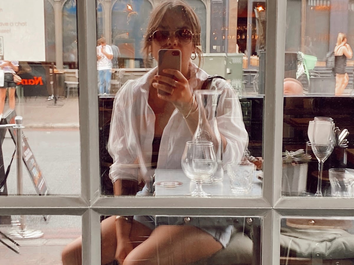 The author taking a selfie in the mirror at an outdoor café.