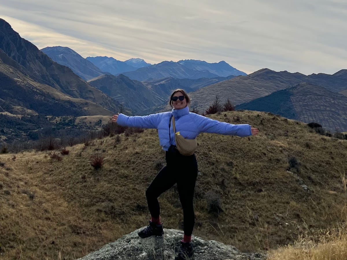 The author spending time in nature, standing on a rock in front of a mountain view.