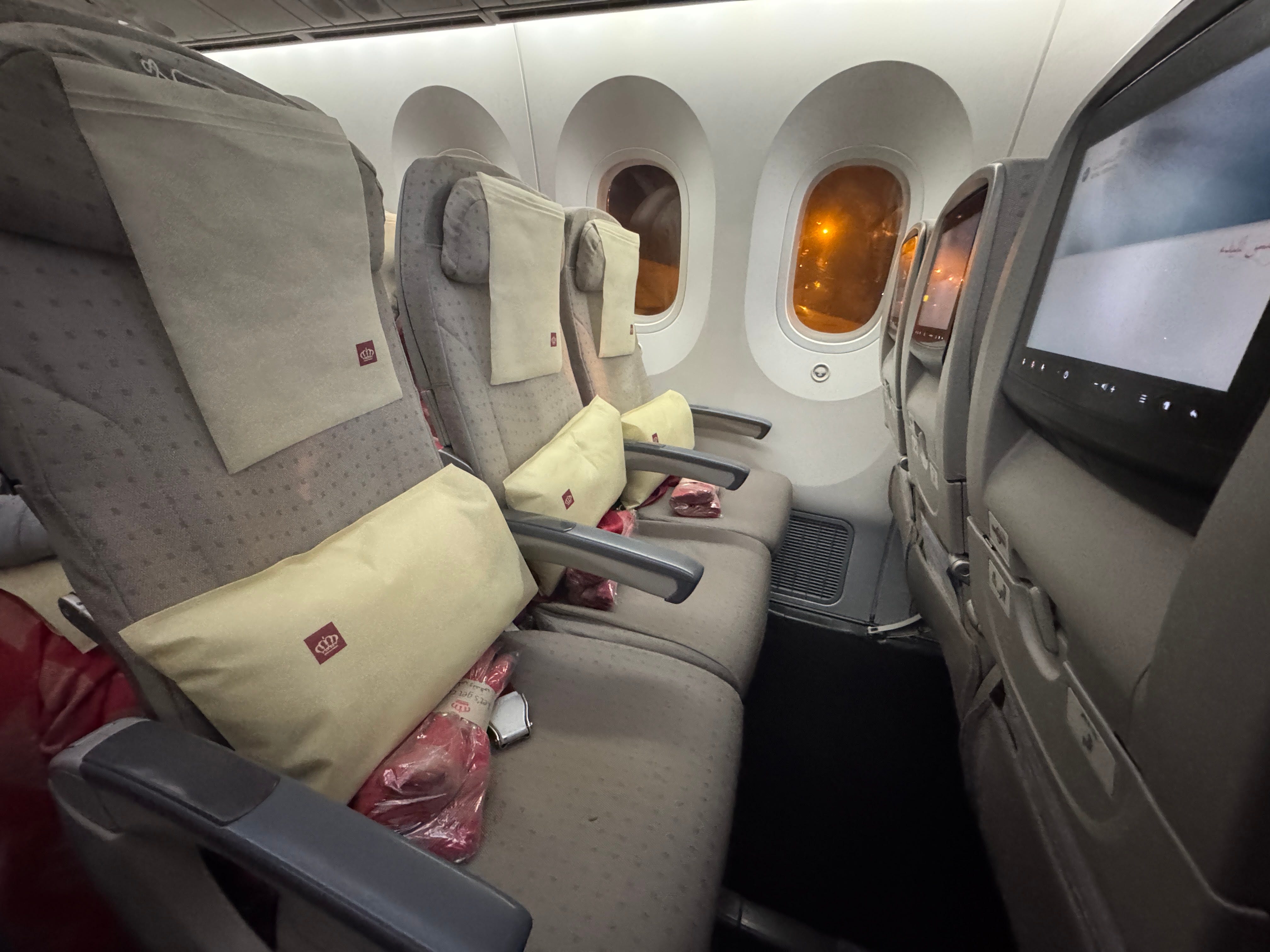 Row of Air Jordanian plane seats with red blankets, pillows on seats